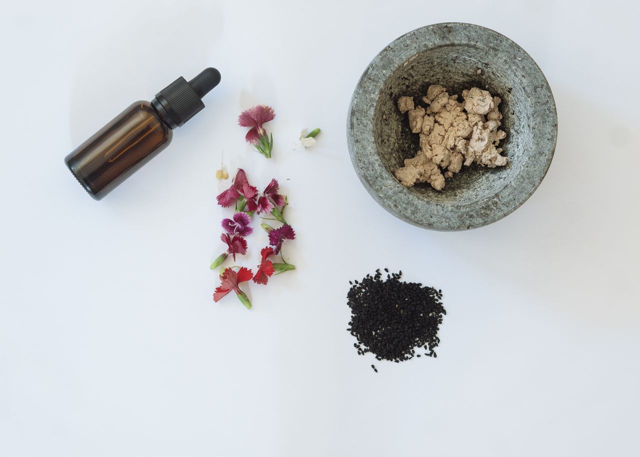 Mastering the First Impression: Your intriguing post title goes here Flat lay of natural skincare ingredients including flowers, black seeds, and a dropper bottle.